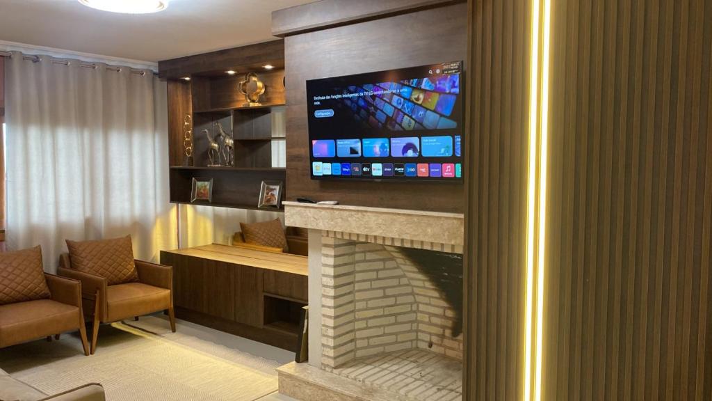 uma sala de estar com lareira e uma televisão por cima em Residencial Don Alfredo-Luxo Gramado 2 km do centro locação de temporada em Gramado