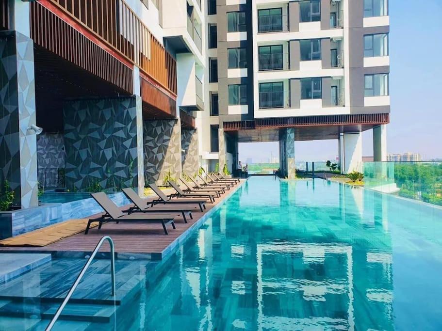 einem Hotelpool mit Liegestühlen und einem Gebäude in der Unterkunft Experience Luxury Living! Spectacular 1-Bedroom Apartment in Thuan An, Binh Duong in Thuan An