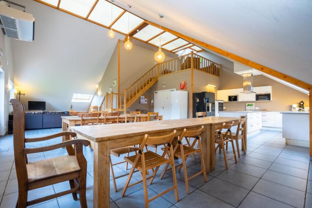 uma cozinha com uma grande mesa de madeira e cadeiras em Au Coeur du Bois em Rendeux