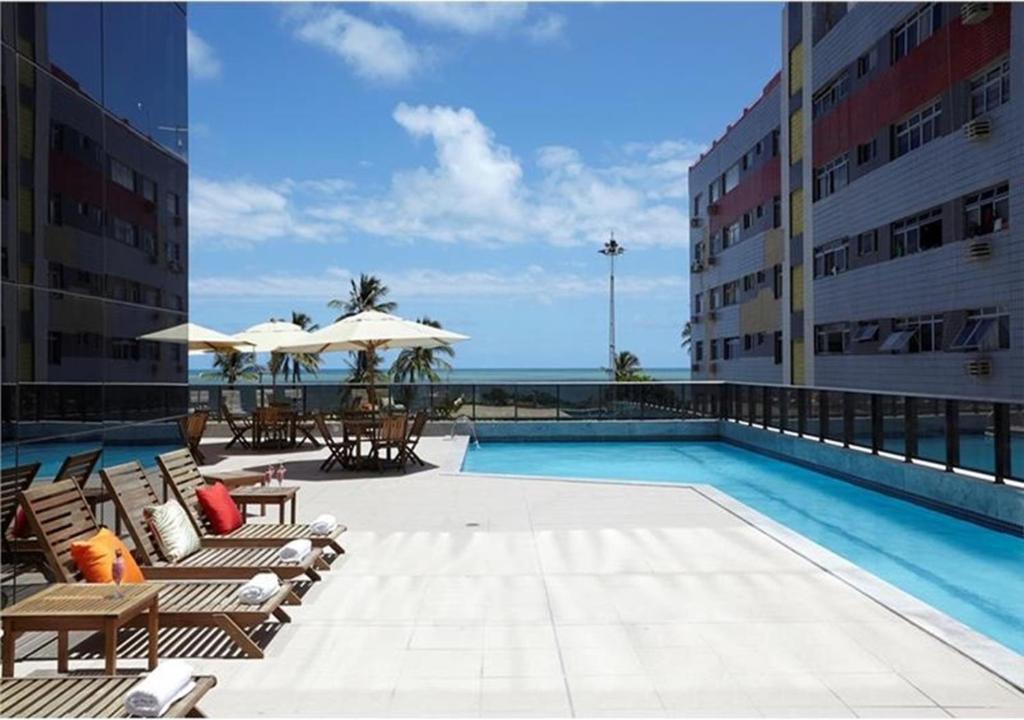 uma piscina com cadeiras e guarda-sóis num edifício em Transamerica Prestige Recife - Boa Viagem no Recife