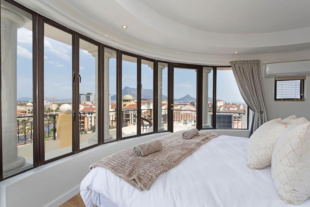 a bedroom with a large white bed and large windows at 30% off Designer Penthouse - backup power - Cape Town in Cape Town