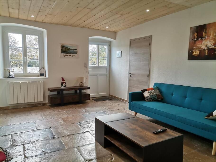 - un salon avec un canapé bleu et une table dans l'établissement L'Alcôve des Ondines, à Rochefort-sur-Nenon