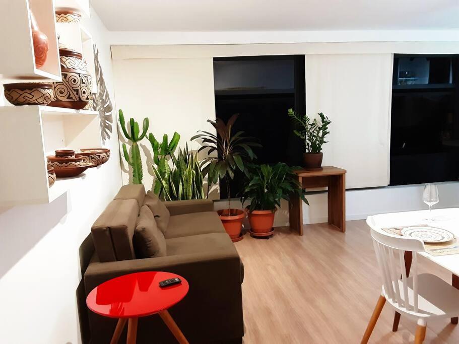 a living room with a couch and a table with plants at Studio116-completo, confortável, amplo, prático in Brasilia