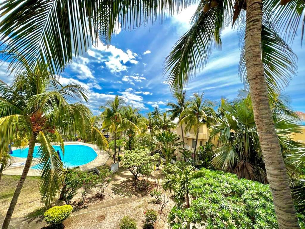 a resort with a swimming pool and palm trees at Lakaz' Tamier in Flic-en-Flac