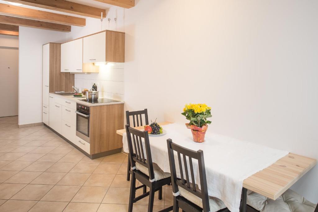 a kitchen with a white table and chairs and a kitchen with a counter at Vintler Apartments in Bolzano