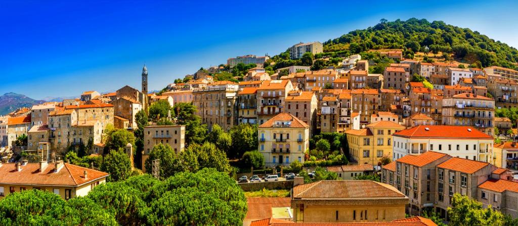 a town on a hill with houses and cars at Hôtel confidentiel Le Grecale in Pianottoli-Caldarello