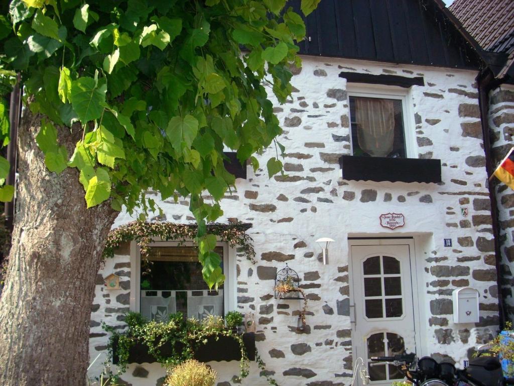 uma casa de pedra com uma árvore em frente em Ferienhaus Zweite Straße em Neuenrade