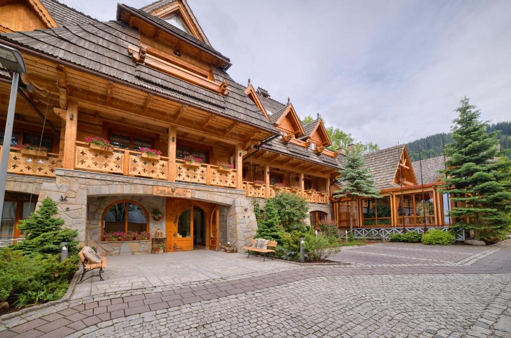 - un grand bâtiment en bois avec une cour devant dans l'établissement Hotel Nosalowy Dwór, à Zakopane