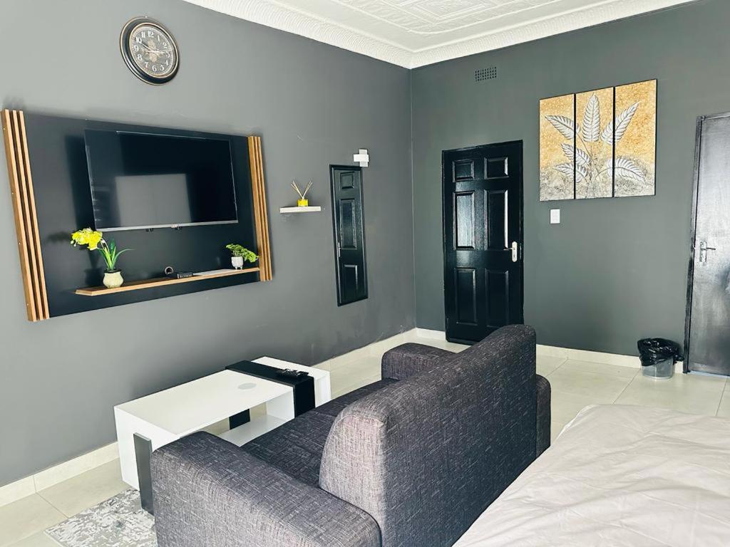een woonkamer met een bank en een tv bij The Curve Apartments Unit 19 in Johannesburg