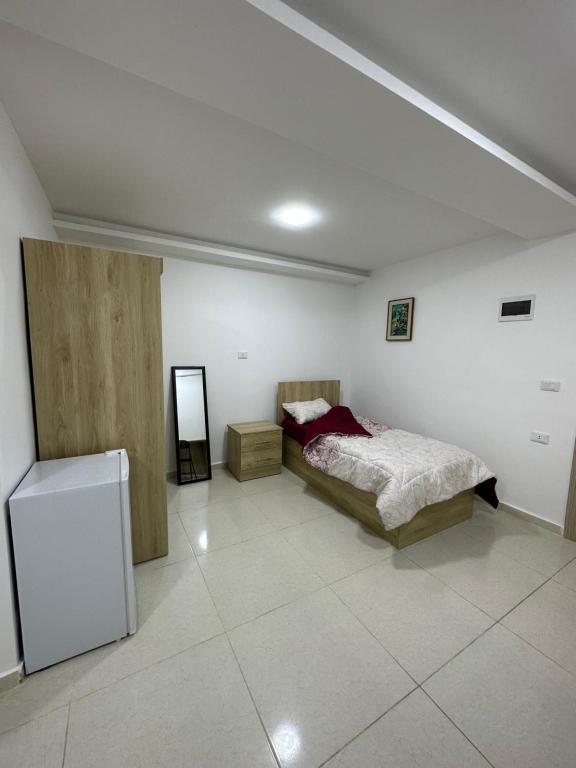 a bedroom with a bed and a refrigerator in it at Karak Plaza Apartments in Kerak