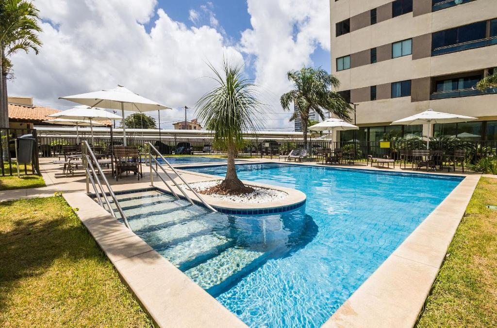 a swimming pool with a palm tree in a building at Áurea Guedes #901A - Apartamento por Carpediem in Natal
