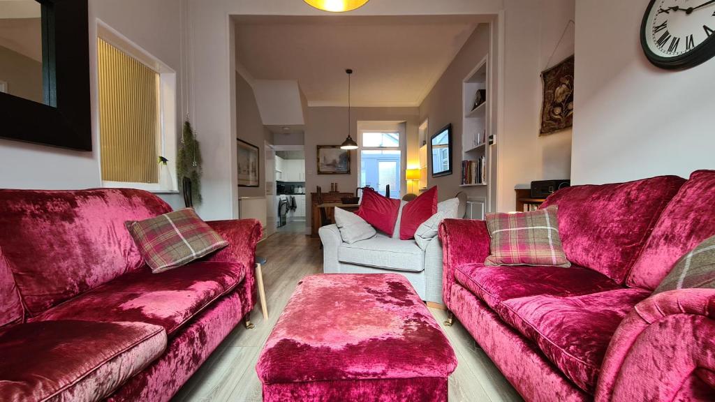 sala de estar con 2 sofás rojos y reloj en Comfy home very close to Cardiff en Barry