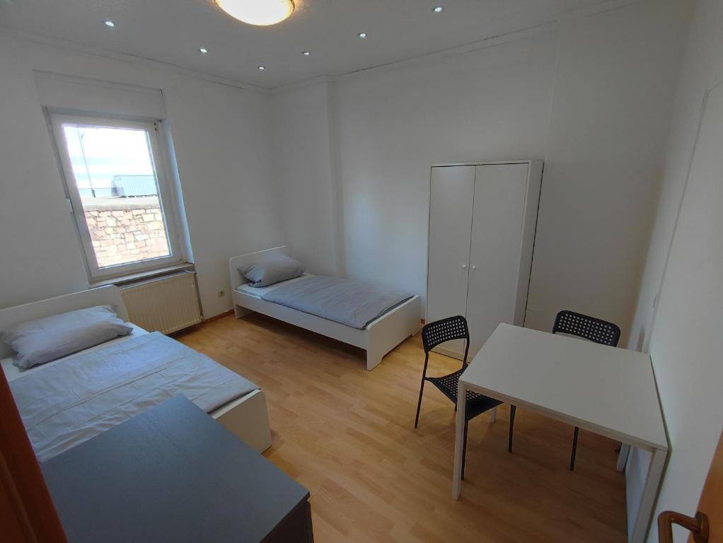 a room with two beds and a table and a desk at Monter24- KH01 Großes Apartment, Monteur Wohnung, 5 Personen, 3 Schlafzimmer, Parkplatz in Bad Kreuznach