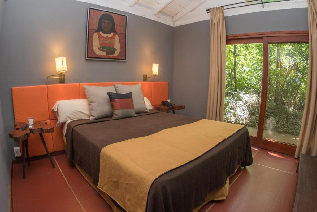 1 dormitorio con 1 cama con cabecero naranja y ventana en Raices Amambai Lodges en Puerto Iguazú
