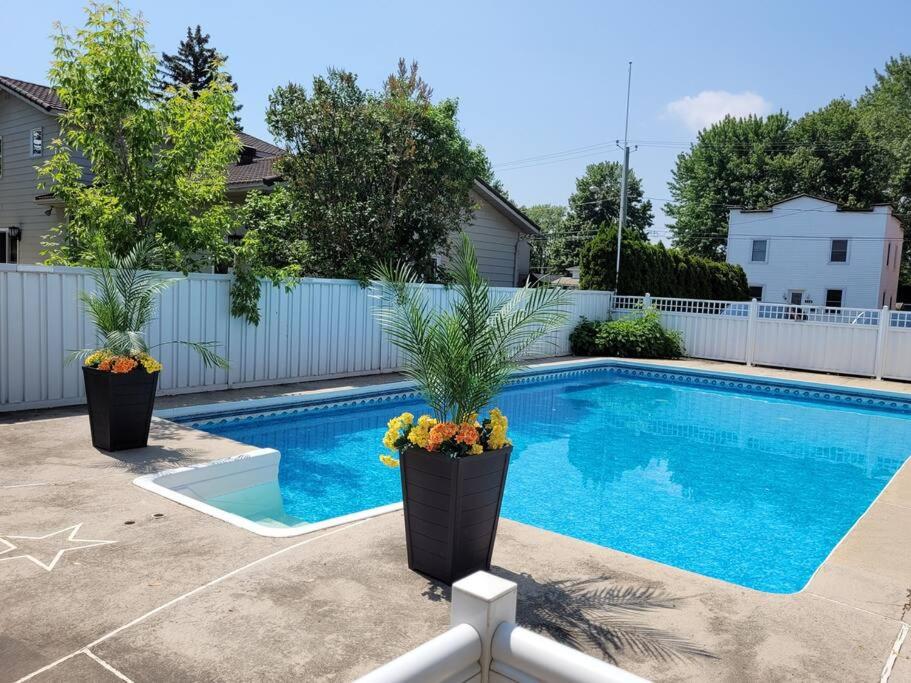 una piscina con dos macetas al lado en PRIVATE POOL AND BACKYARD * BBQ * 6 BEDS * 5 MIN. FROM MTL, en Longueuil