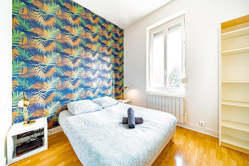 a bedroom with a large bed with a tropical wallpaper at Le petit Raspail-Appartement rénové-Gratte-Ciel in Villeurbanne