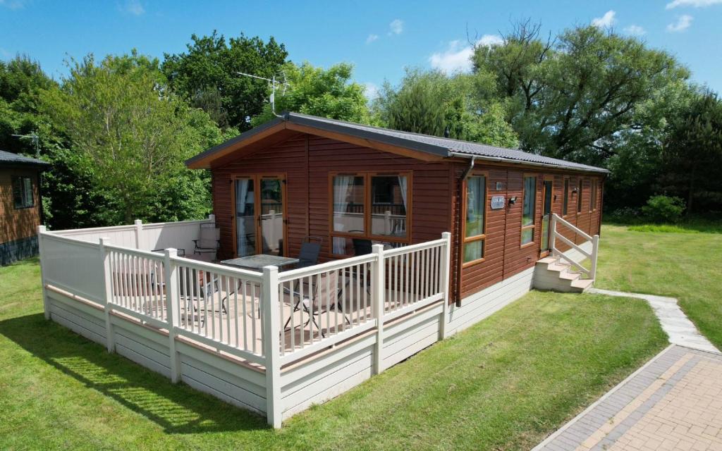 a small wooden cabin with a white fence at Tulip Lodge with Hot Tub in Malton