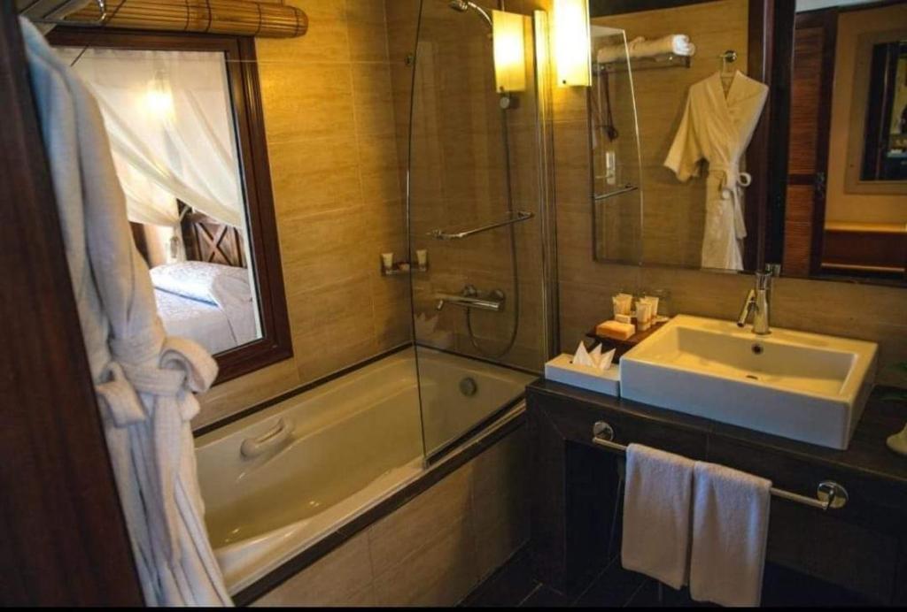 y baño con bañera, lavabo y espejo. en Domina coral bay elisir SPA en Sharm El Sheikh