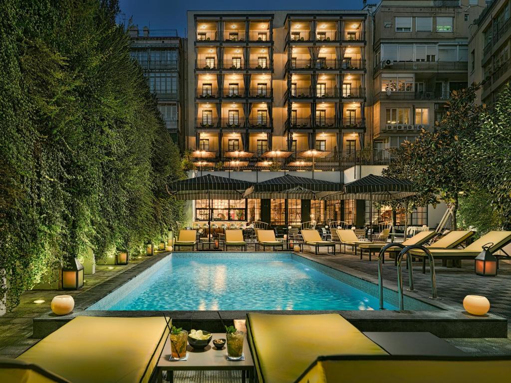 un hotel con piscina di fronte a un edificio di H10 Metropolitan 4* Sup a Barcellona