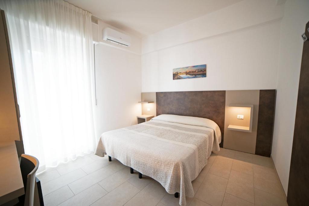 a bedroom with a white bed and a large window at Hotel Mara in Rimini