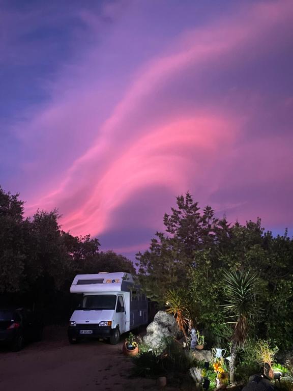 a rv parked in a parking lot with a pink sky at Camping car fixe dans la campagne in Pianottoli-Caldarello