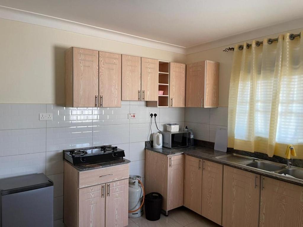 eine kleine Küche mit Holzschränken und einem Waschbecken in der Unterkunft Munyonyo Apartment in Kampala