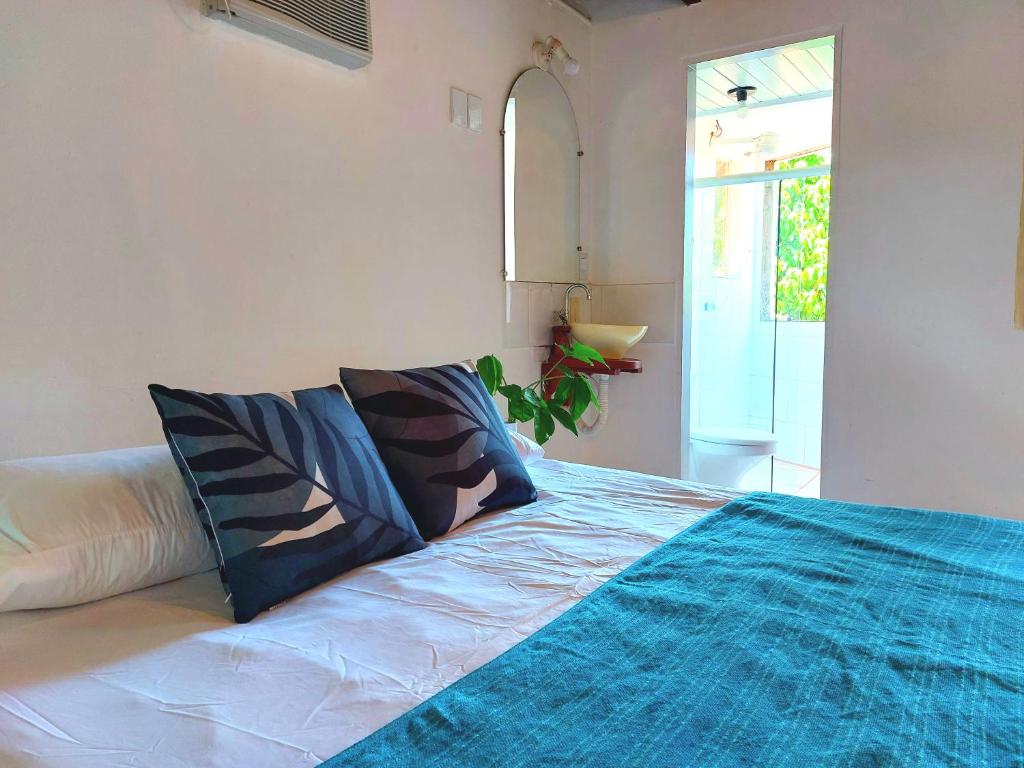 a bedroom with a bed with blue sheets and a window at Circular Guest House in Itacaré