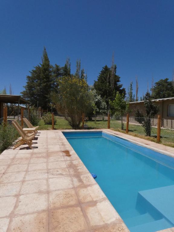 una piscina blu con una panchina accanto di Cabañas EL AGUARIBAY a Barreal