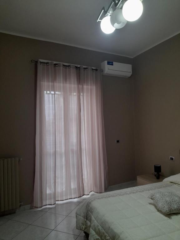 a bedroom with a bed and a window with curtains at Casa Brezza marina in Barletta