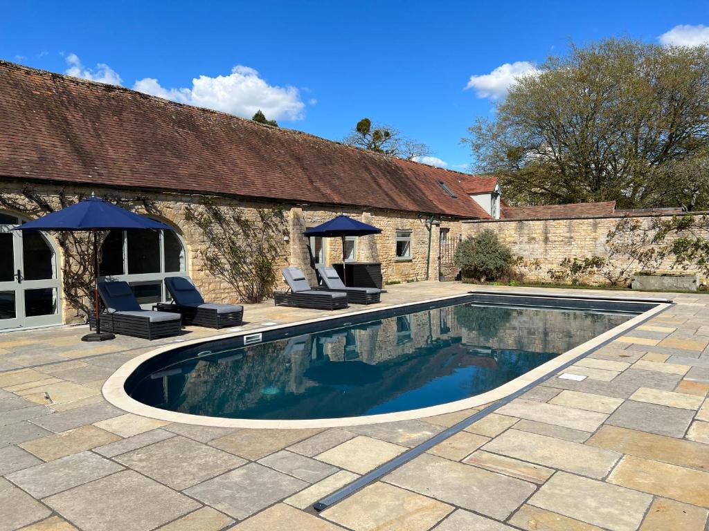 una piscina con 2 sillas y una casa en Luxury Cottage with Swimming Pool en Bredon
