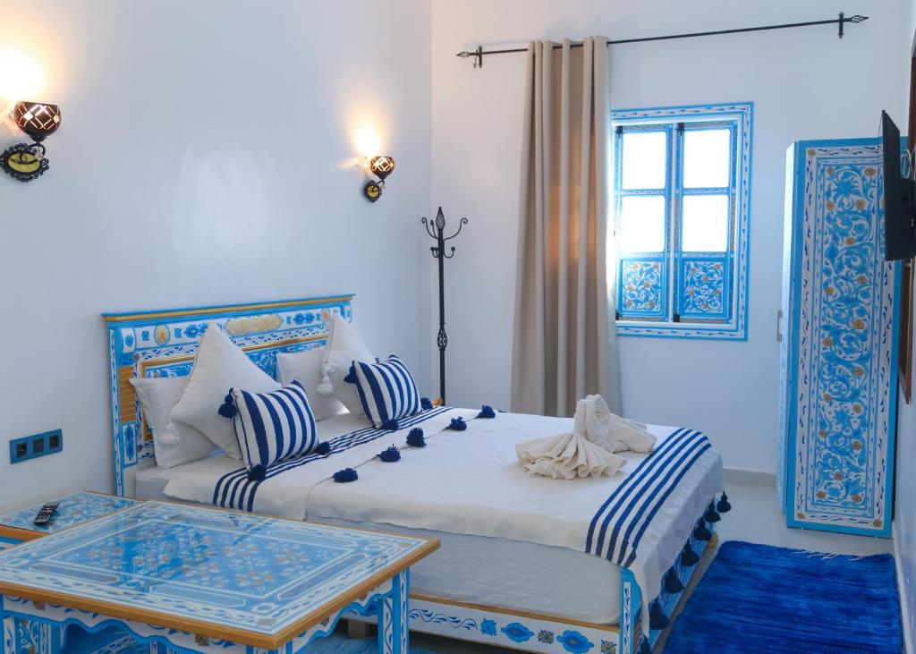 a bedroom with two beds and a table and a window at CASA BLUE PEARL in Chefchaouen