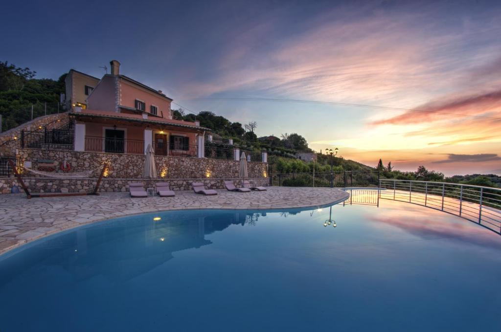 a villa with a swimming pool in front of a house at Agallis Corfu Residence in Sokrakion