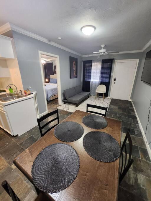 Blue Shark G9 - Midtown 1BR King Suite في هيوستن: مطبخ وغرفة معيشة مع طاولة وكراسي خشبية