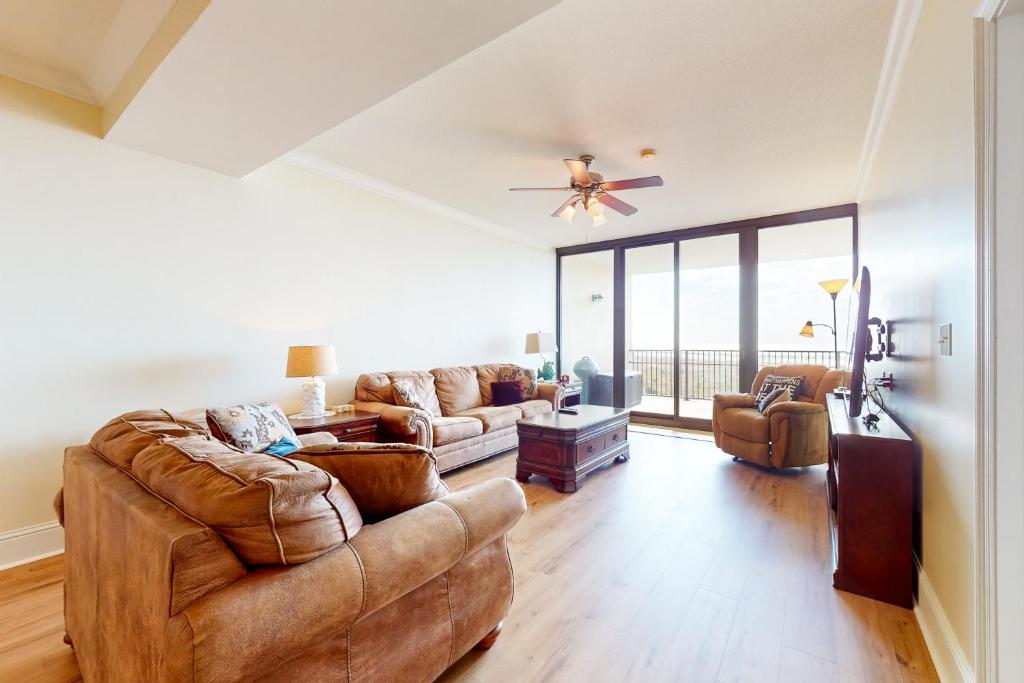 sala de estar con muebles de cuero y ventilador de techo en Holiday Isle 413 en Dauphin Island