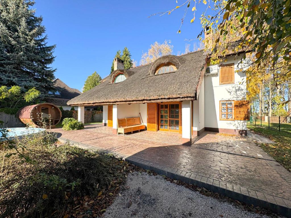 une maison avec un toit de chaume et une terrasse dans l'établissement Relax & Fishing, à Békésszentandrás