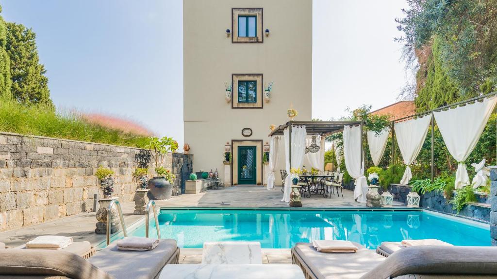 ein Haus mit einem Pool mit Chaiselongues in der Unterkunft Villa Urbis Taormina, luxury villa in the heart of Taormina with swimming pool & lift in Taormina
