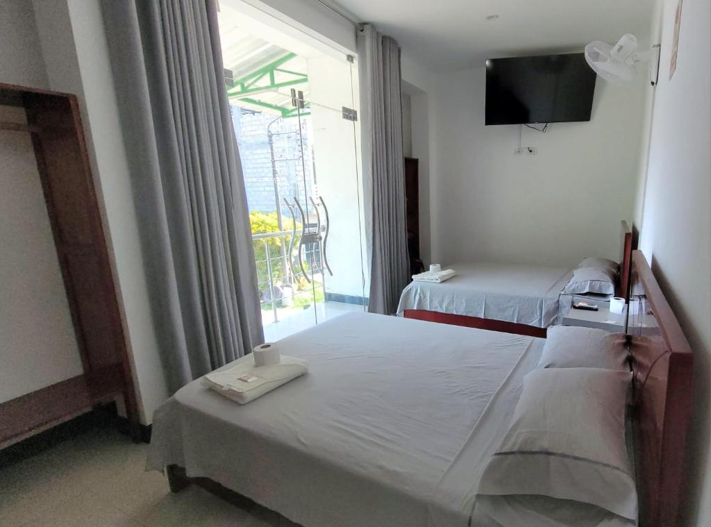 a bedroom with two beds and a large window at Hospedaje Vista Paraíso in Tingo María