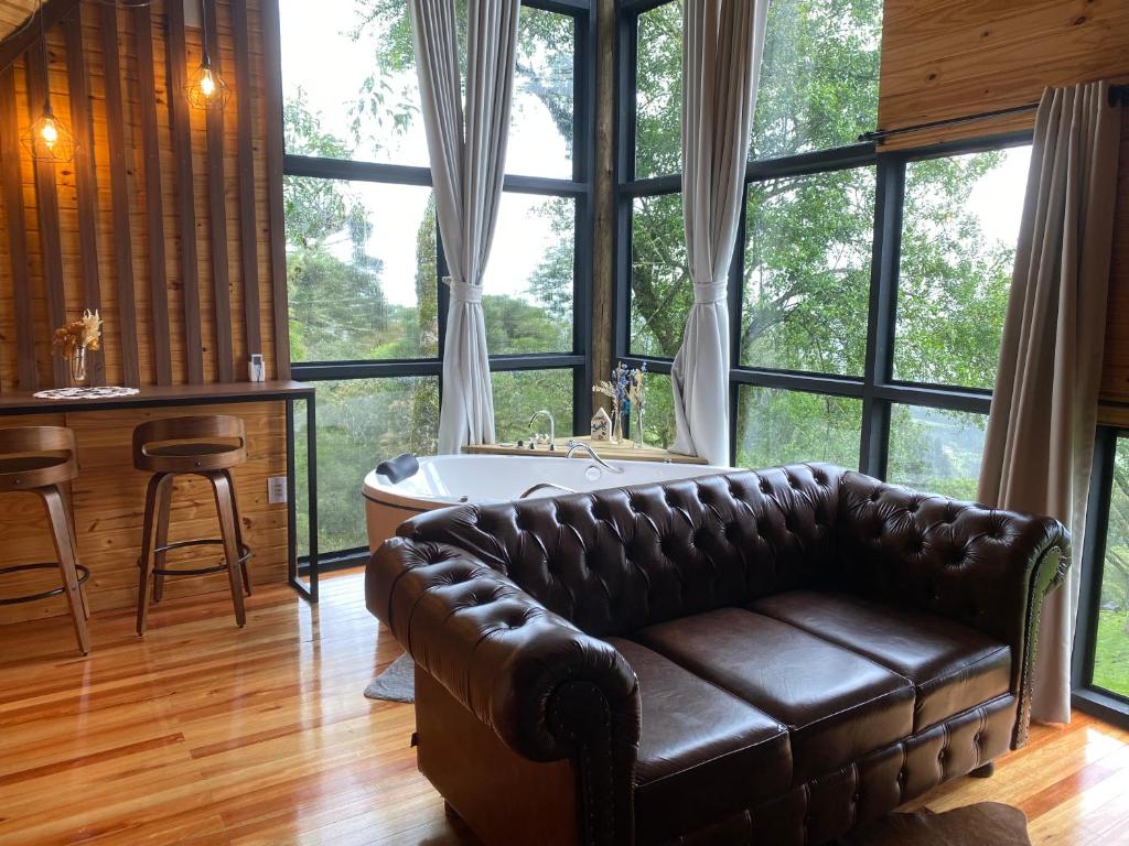a living room with a leather couch and a tub at Aslaug Chalé in Urubici