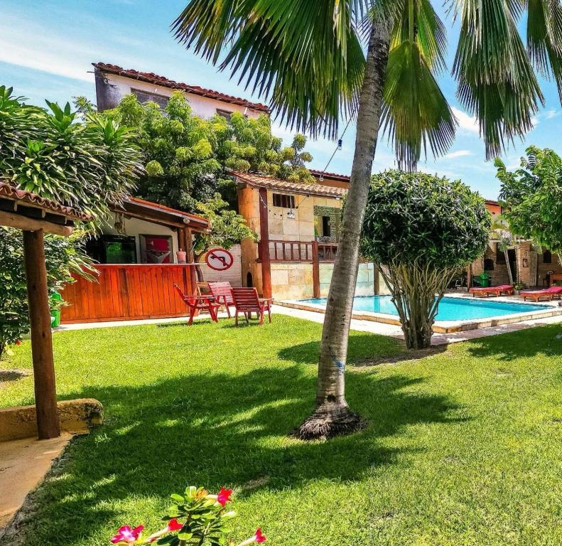 une maison avec un palmier et une piscine dans l'établissement Trilha dos Ventos Cumbuco, à Cumbuco