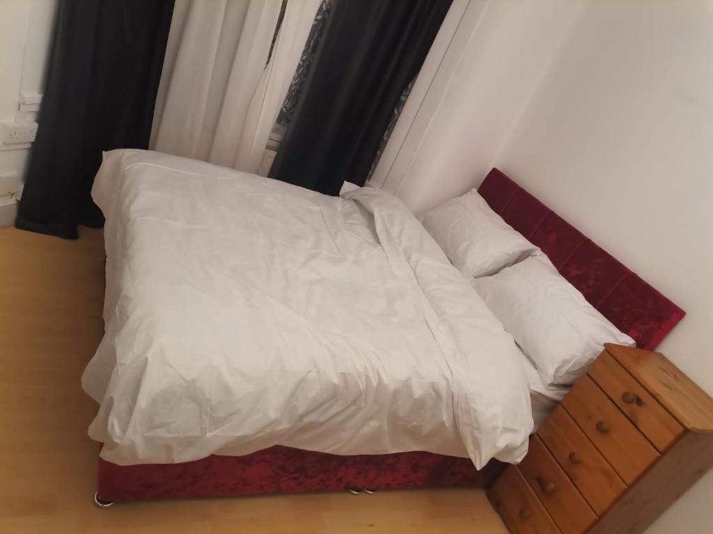 a bed with white sheets and pillows in a room at Luxury Double Room near London Seven Kings Train Station in Seven Kings
