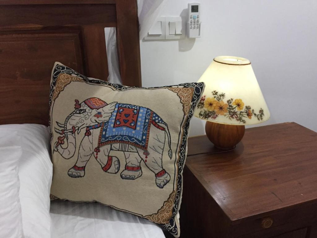 a bed with a pillow and a lamp on a table at Tropical Villa in Galle