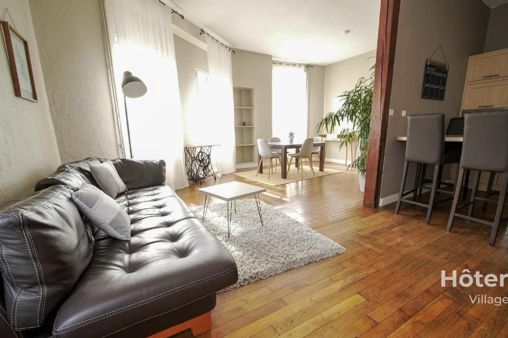 ein Wohnzimmer mit einem Ledersofa und einem Tisch in der Unterkunft The House of Monthléry Comfort in Limoges in Limoges