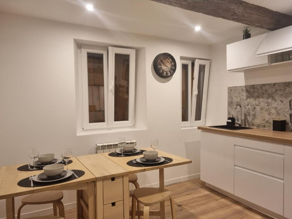 une cuisine avec une table et des chaises et une horloge au mur dans l'établissement Le panier Vieux-Port Marseille, à Marseille