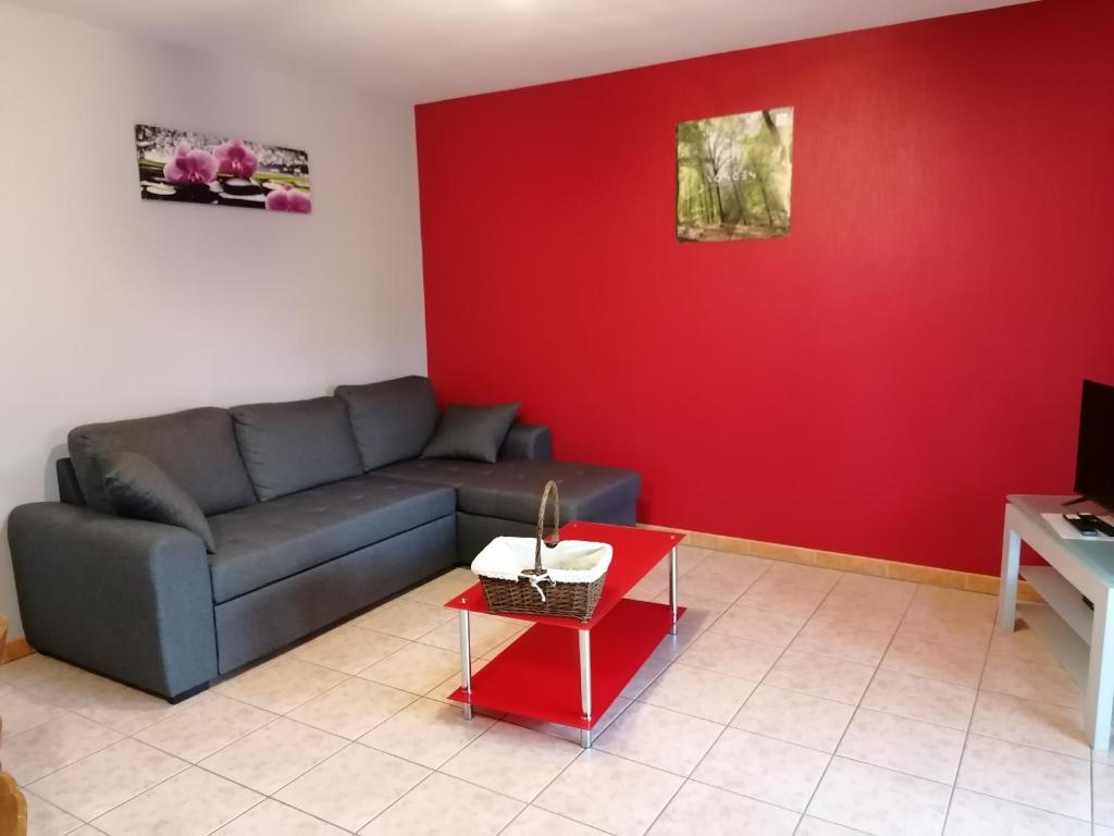 een woonkamer met een bank en een rode muur bij AIR PAIX LE MONT in Herpelmont