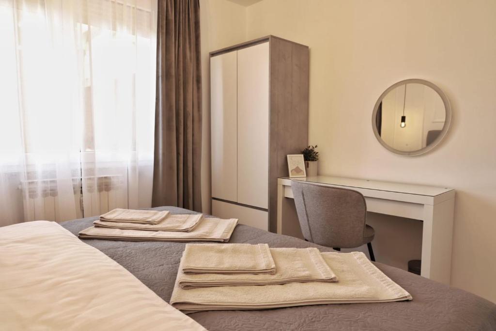 een slaapkamer met een bed, een bureau en een spiegel bij Apartman Nila in Vukovar