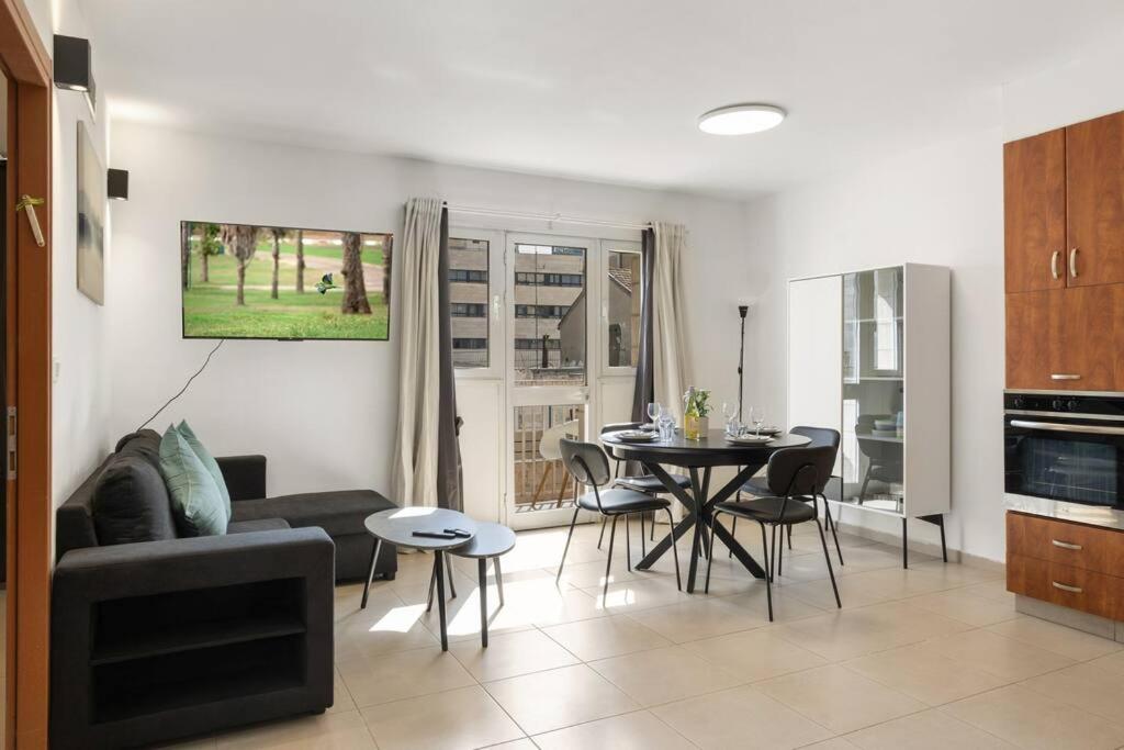 een woonkamer met een bank en een tafel met stoelen bij Beautiful Ben Yehuda Apartment in Jeruzalem