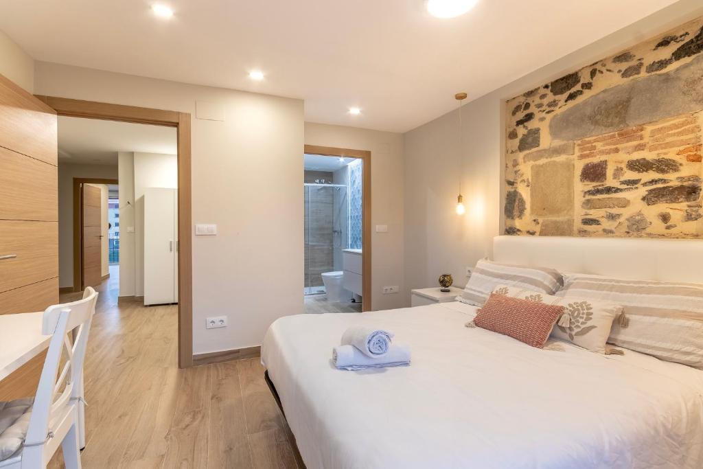 1 dormitorio con 1 cama blanca grande y pared de piedra en Apartamento El Toisón de Oro 22 Garaje gratis en Bilbao