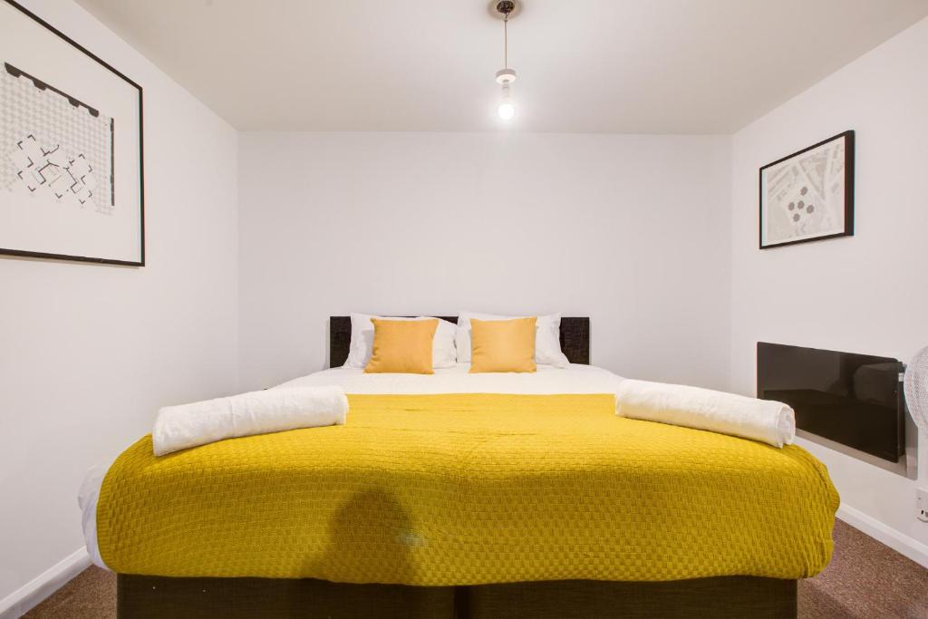a bedroom with a bed with a yellow blanket at Town Centre Apartment in Croydon