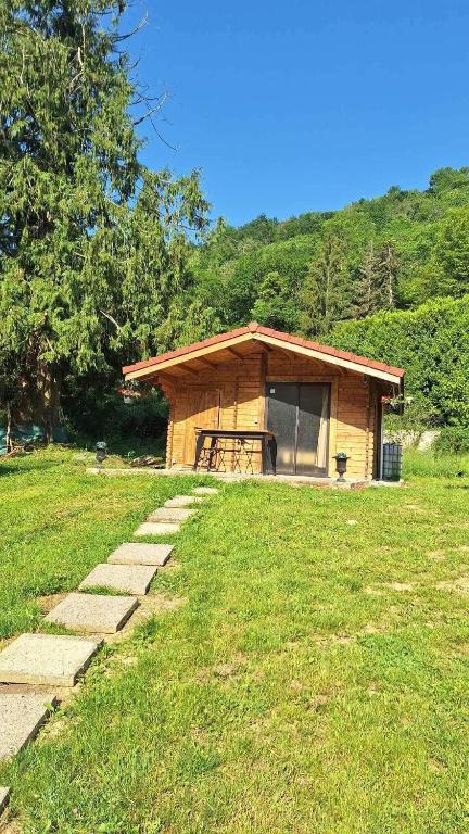 a small cabin in a grassy field with a building at Le CHALET in Pressins