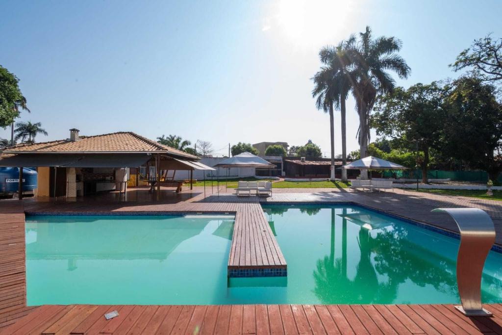 a large swimming pool with a patio and a house at Chácara Luxuosa em Goiânia UPR0011 in Goiânia